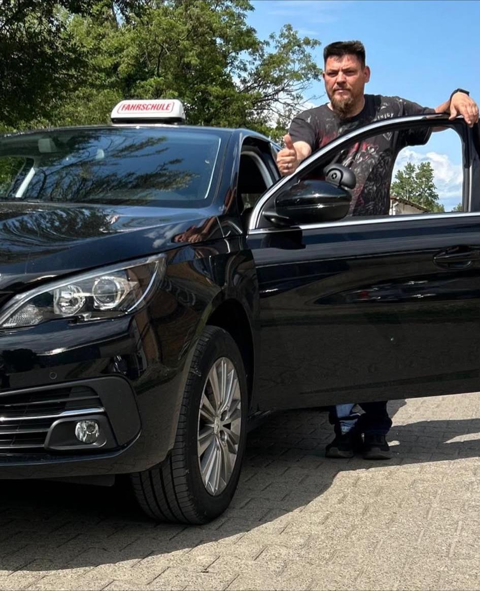 Fahrlehrer Peter Dost am schwarzen Fahrschulauto der Fahrschule Palme in Eberswalde